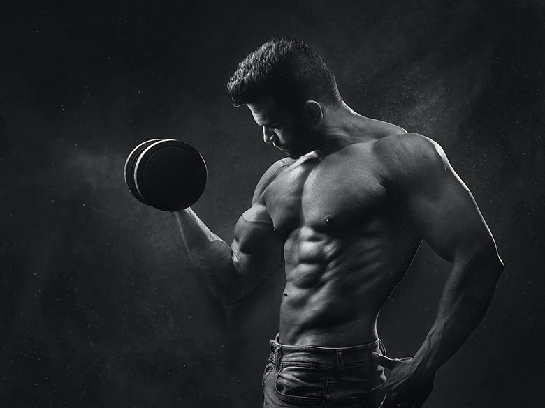 Черно-белое фото мускулистого мужчины с гантелей