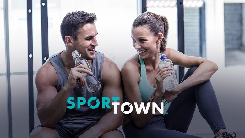 Спортивные парень и девушка сидят в фитнес-клубе SportTown с бутылками воды в руках.