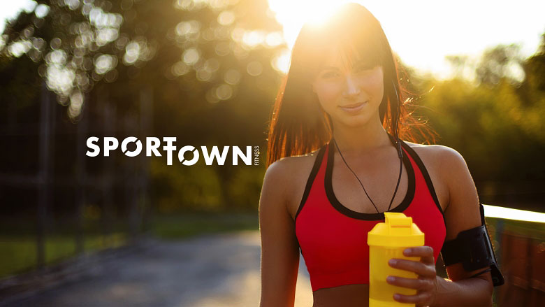 Девушка в спортивном топе и многоразовой бутылкой воды на закате и надписью SportTown