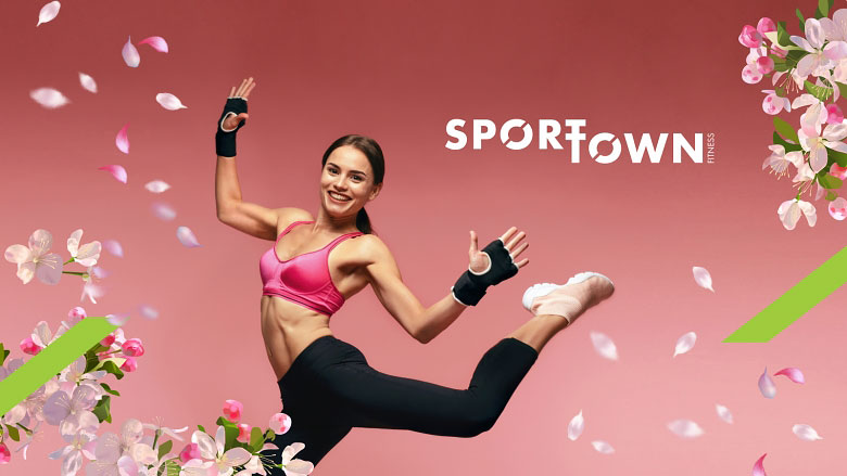 Спортивная девушка прыгает в цветущей сакуре на фоне надписи SportTown Fitness